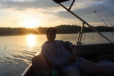 A person relaxes in a boat with a fishing rod, enjoying the...