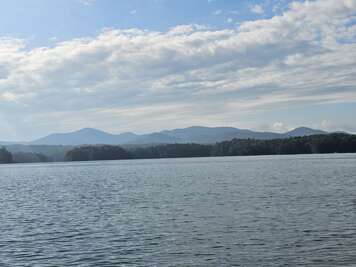 A tranquil Lake Blue Ridge, GA stretches out under a sky dotted...