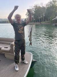 A man triumphantly raises his fists while holding a large fish...