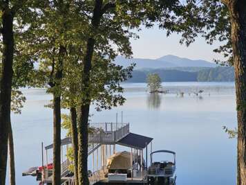 Trees frame a tranquil lakeside setting with a docked boat,...