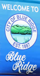 Bright blue signage invites travelers to explore the City of...