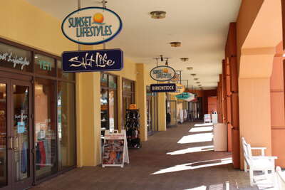 A sunlit shopping corridor in Harbor Walk Village  lined with...