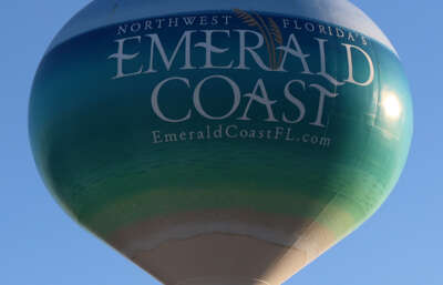 A large water tower under a clear sky, emblazoned with the...