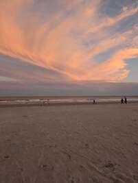 The image captures a serene beach scene at sunset, with soft...