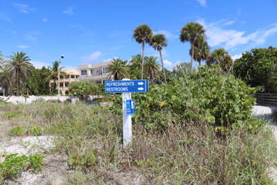 A sign for refreshments and restrooms stands in front of lush...