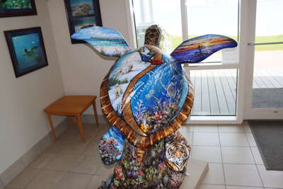 A creatively painted turtle sculpture, adorned with vibrant...