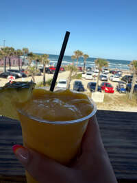 A close-up of a hand holding a frozen drink with a straw,...