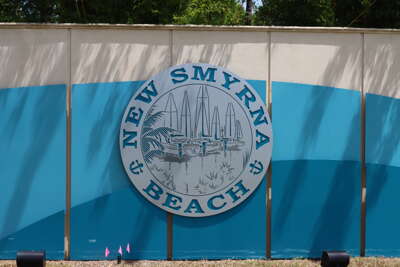 A roadside barrier displays a large emblem representing New...