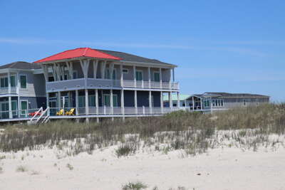 A two-story beach house on Oak Island, NC on a sandy shore...
