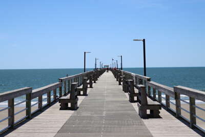 A long wooden pier on Oak Island, NC stretches into the...