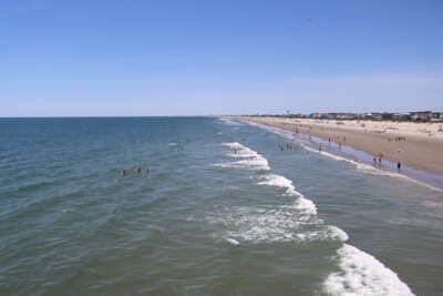 Waves gently roll onto a sandy beach, where people are...