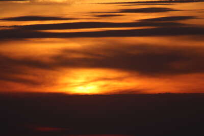 A vibrant sunset on Oak Island, NC with deep orange and gold...