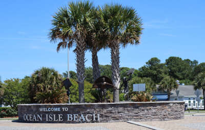 Palm trees frame a welcoming sign for Ocean Isle Beach, NC...