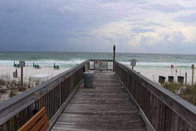 A wooden boardwalk leads directly to a sandy beach under...