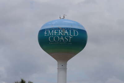 A water tower stands under a cloudy sky, proudly displaying...