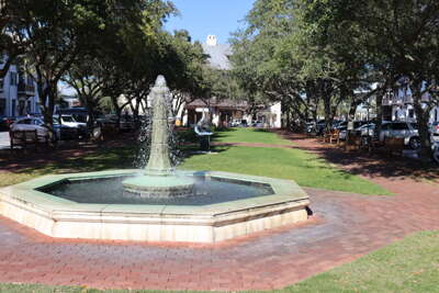A brick-lined pathway leads to a fountain in the center of a...