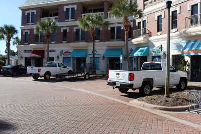 The image captures a sunny street lined with various businesses...