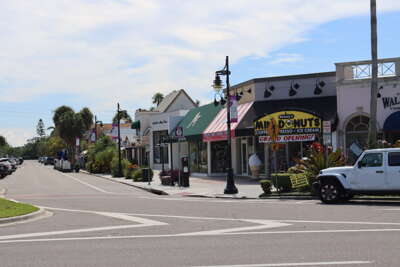 Sunlit streets lined with diverse storefronts, including a...