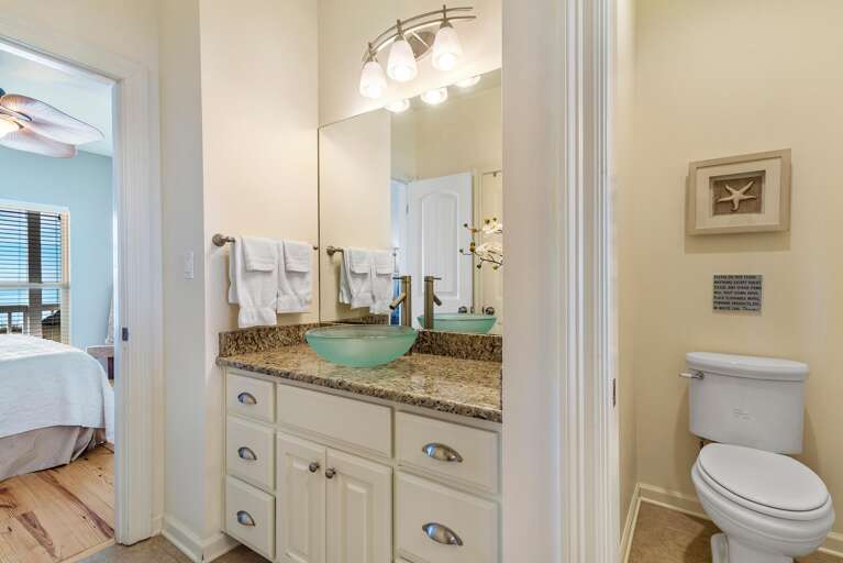 Bathroom vanity with granite countertop, frosted glass vessel sink, brushed nickel faucet, and large mirror.