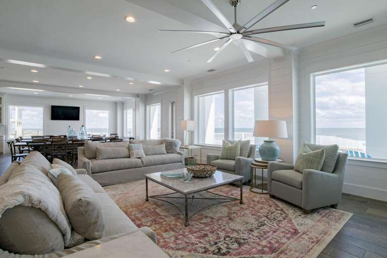 Living room with gray sofas and armchairs around a metal-framed marble coffee table on a patterned rug.