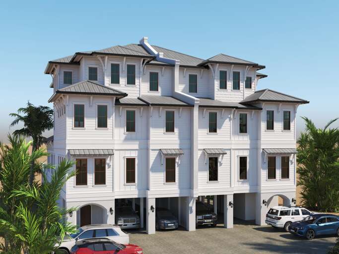 White exterior with multiple windows, gray metal roofs, and covered parking beneath the raised three-story house.