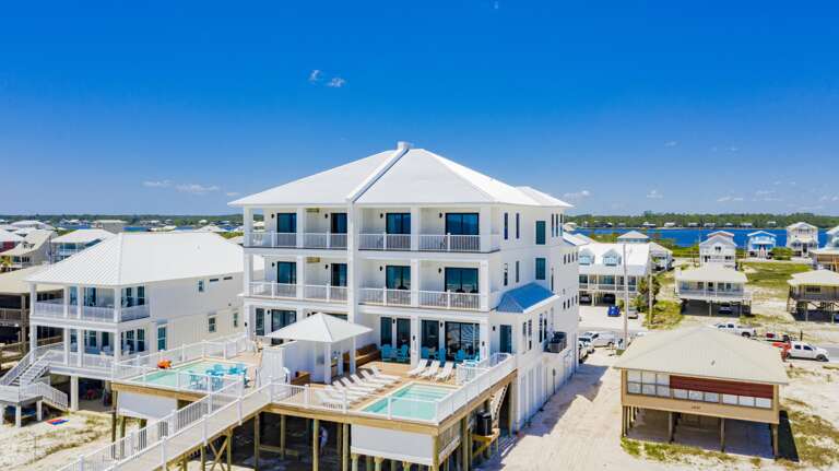 Two elevated pools flank a spacious sun deck with white loungers and turquoise Adirondack chairs.