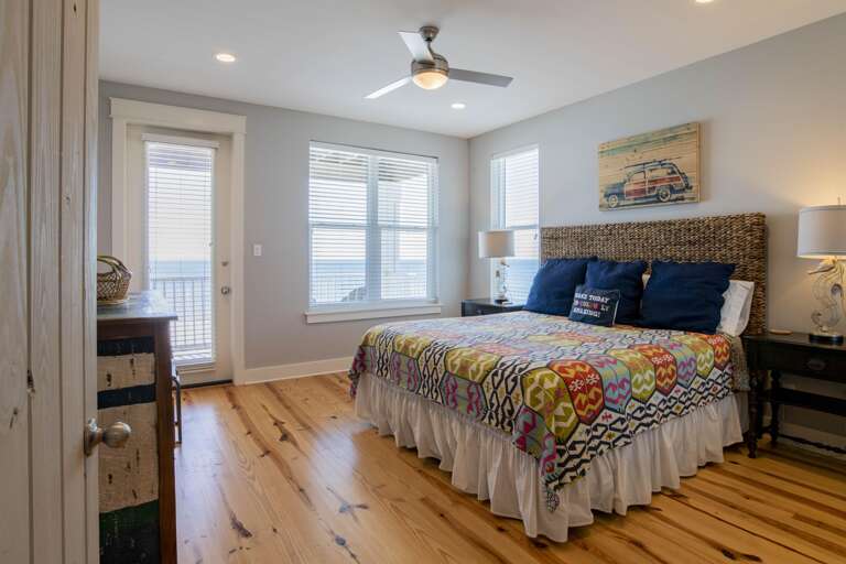 Natural light fills the bedroom with hardwood floors, dark wood nightstands, and a ceiling fan overhead.