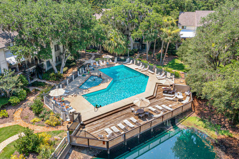 Aerial View Of A Lush, Leafy Locale With A Large Pool, Loungers, And Linked Decks