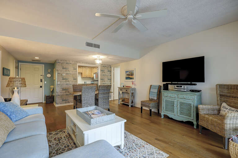Living Room With Light Blue Seating, Wooden Walls, Television, And Ceiling Fan In Vacation Rental