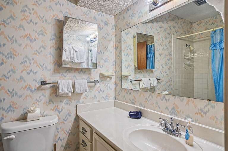 Your private bathroom features a fresh, clean design with soft patterned wallpaper, crisp towels, and a tiled showerâeverything you need to unwind after exploring.