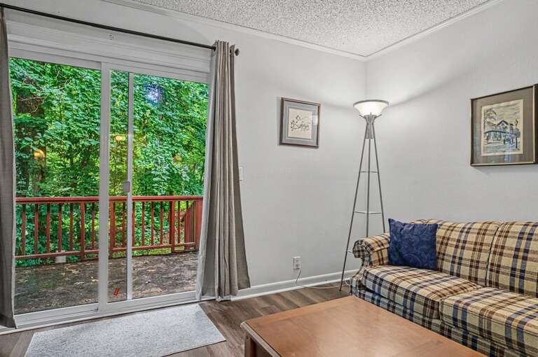 Relax in your cozy living area with natural light streaming through sliding doors that open to a peaceful wooded view and private deck.