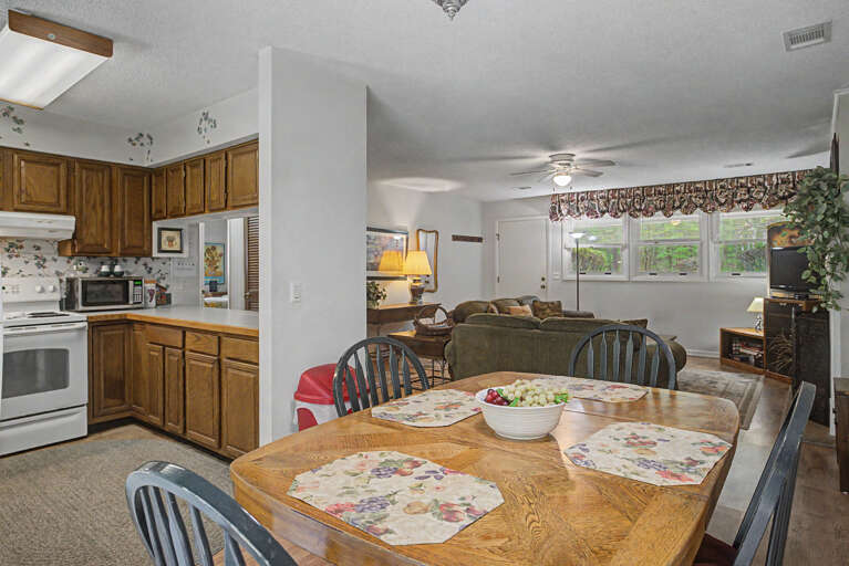 Gather around the welcoming dining table where your group can share meals and stories, with the fully-equipped kitchen just steps away and the cozy living room flowing seamlessly beyond.