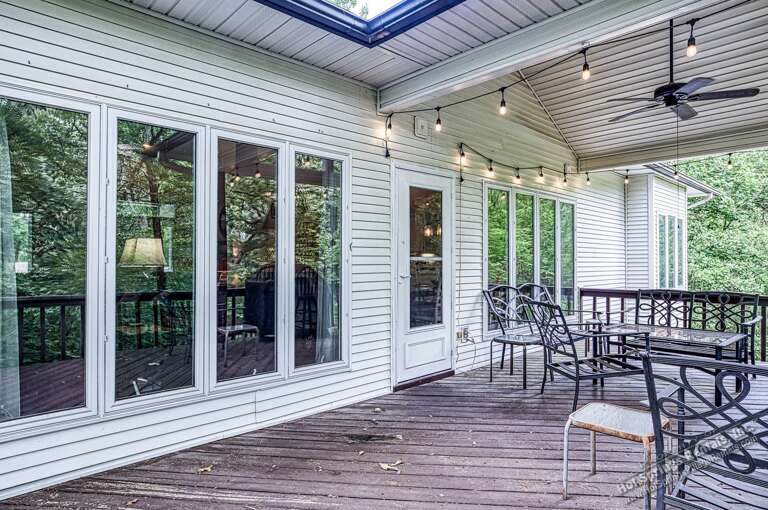 The covered deck combines indoor comfort with outdoor relaxation, featuring string lights, dining space, and a skylight overhead. Perfect for morning coffee or evening gatherings year-round.