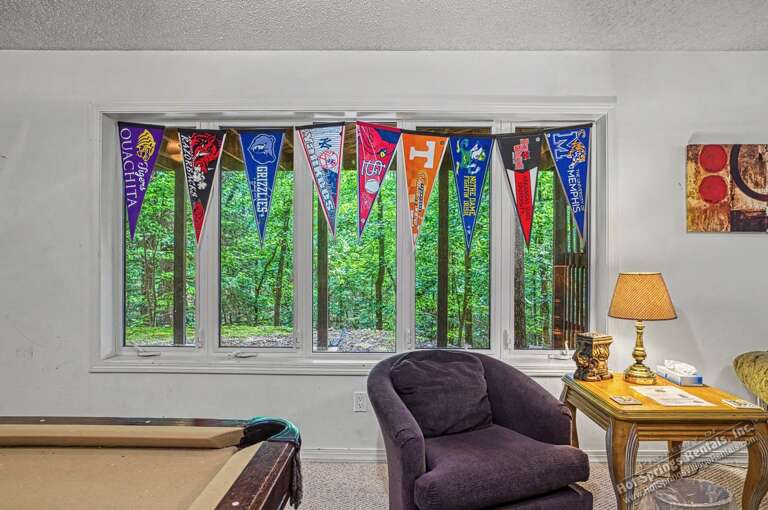 Relax in your cozy game room with colorful pennants and a peaceful garden view, perfect for unwinding after a day of adventure.