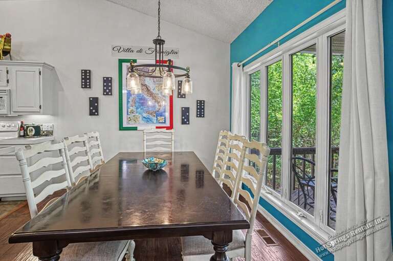 Gather around the warm dining table for meals and games, with bright natural light streaming through the patio doors to your green outdoor retreat.