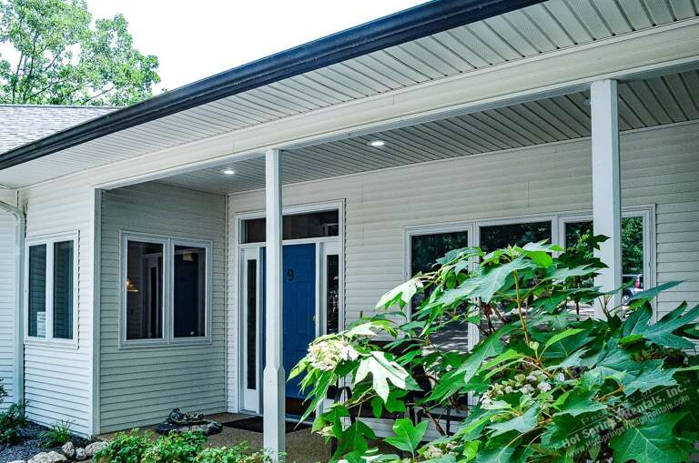 Modern entrance with covered porch and lush greenery welcomes guests to this well-maintained property with multiple units.