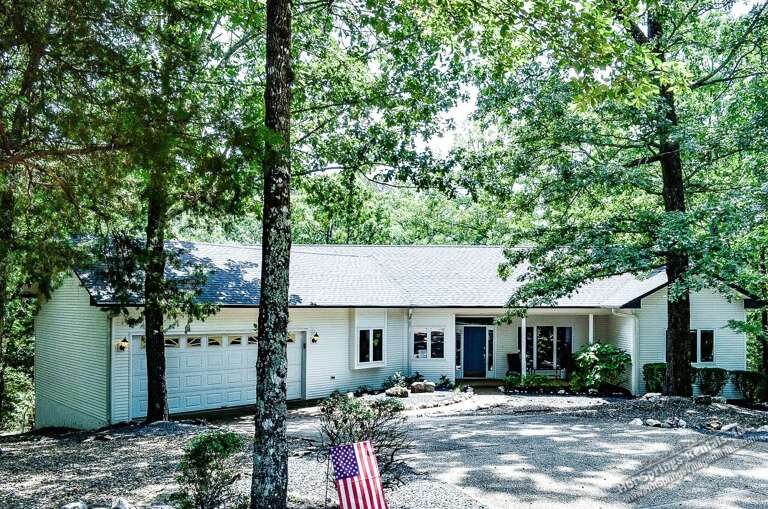 A peaceful vacation retreat nestled among mature trees, offering a serene wooded setting with convenient parking and a welcoming exterior.