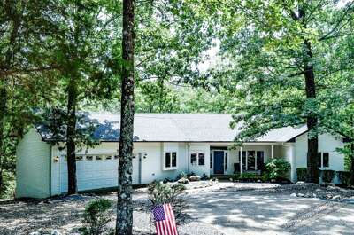 A peaceful vacation retreat nestled among mature trees, offering a serene wooded setting with convenient parking and a welcoming exterior.