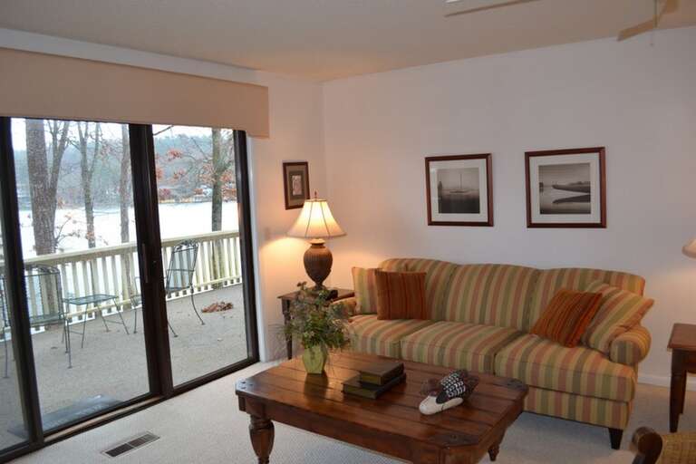 Relax in your cozy living room with its inviting striped sofa and warm lamp, while soft winter light filters through the glass doors to your private balcony overlooking the peaceful, snow-dusted landscape.