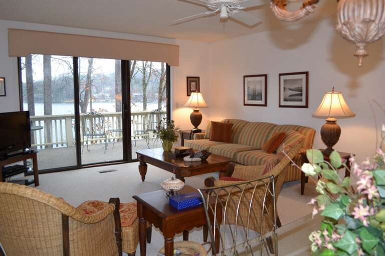 Settle in and watch the lake shimmer through expansive windows, where your cozy living space opens directly onto a private balcony overlooking the water.