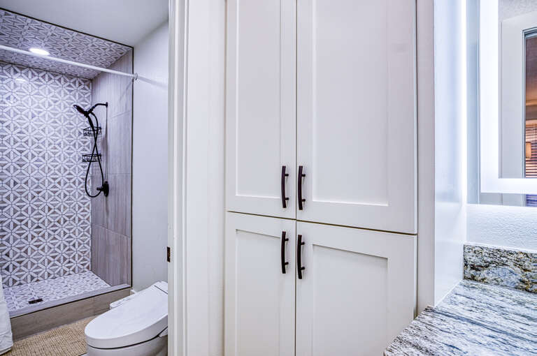 Step into your spa-like bathroom featuring elegant patterned tile, rainfall shower, and custom storage for a truly relaxing retreat.