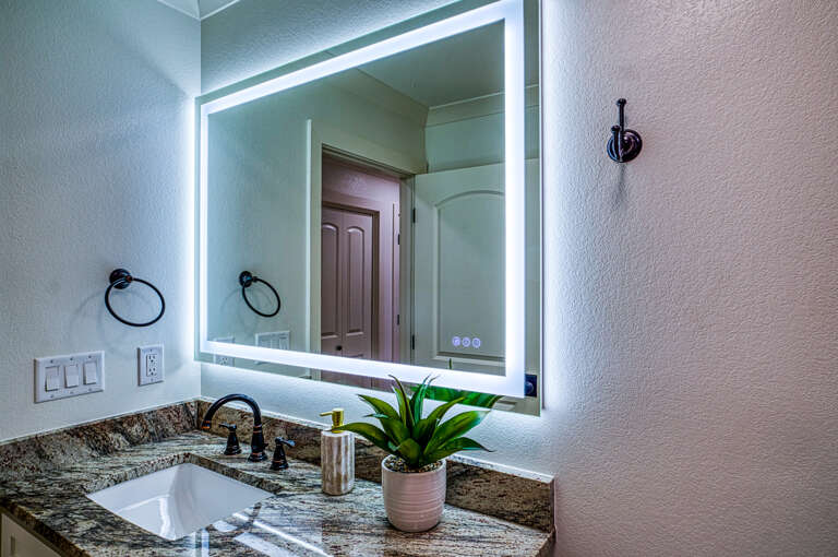 Refresh in your modern bathroom featuring LED-lit vanity mirror, granite countertops, and thoughtful touches that make mornings feel luxurious.