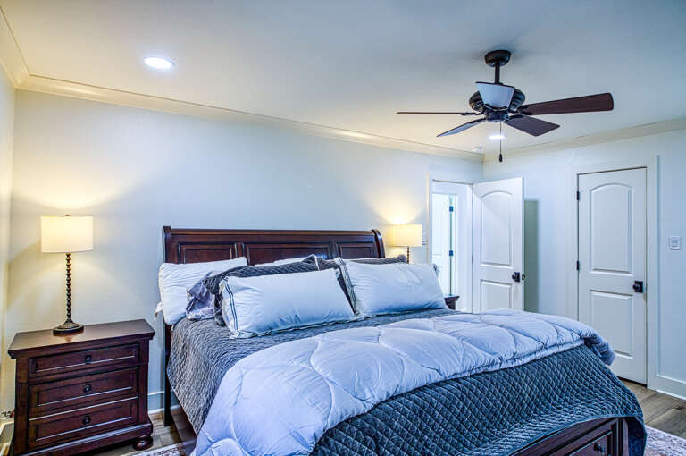 Rest in your spacious bedroom with plush bedding and gentle ceiling fan creating the perfect sleep sanctuary.