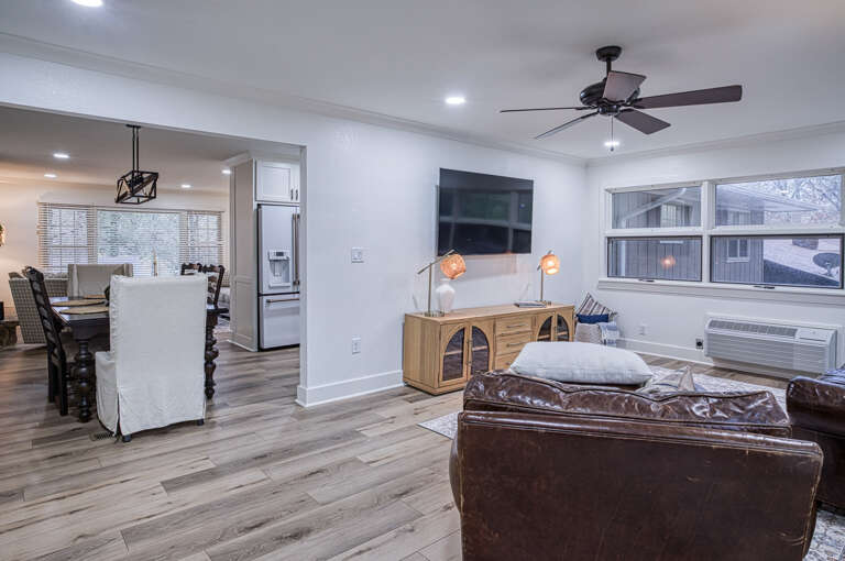 Relax in your open-concept living space with leather seating, ceiling fan, and stunning natural light from large windows.