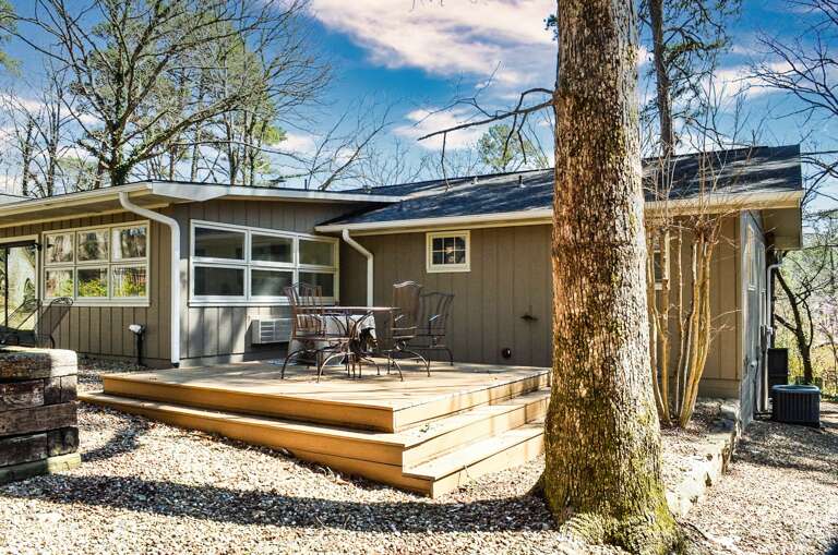 Modern cabin nestled among towering trees with a spacious deck for morning coffee and evening relaxation in nature's embrace.