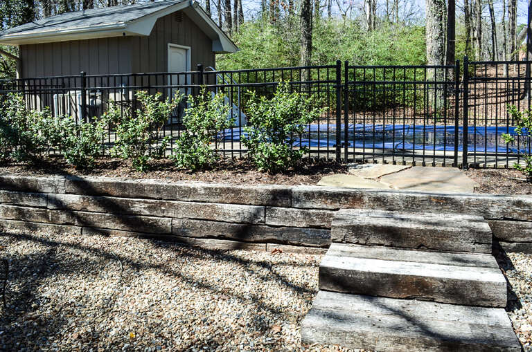 This cabin retreat features a fenced swimming pool nestled among mature trees, offering a perfect woodland escape for relaxation.