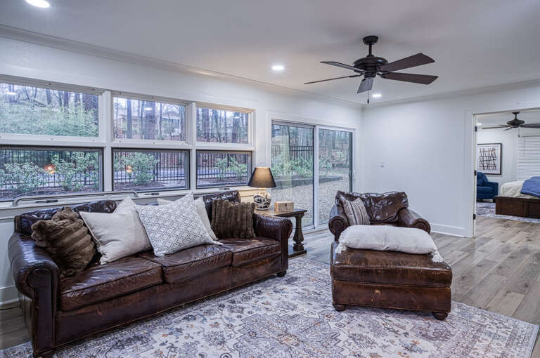 Relax in your spacious living room with rich leather seating and large windows overlooking peaceful wooded surroundings.