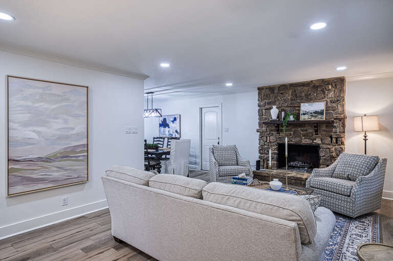 Sink into plush seating by your stone fireplace, where elegant artwork and warm lighting create the perfect retreat for cozy evenings together.