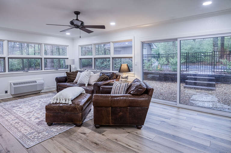 Sink into rich leather seating while natural light floods your spacious retreat through floor-to-ceiling windows overlooking serene outdoor spaces.