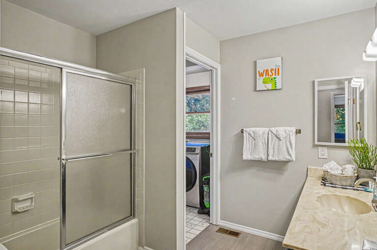 Fresh towels and a bright, clean space await you in this inviting bathroom, connecting seamlessly to your private laundry area for added convenience.